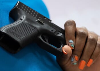 A woman holds a Glock pistol.