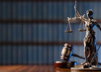 A statuette of Lady Liberty stands beside a gavel and a wooden block.