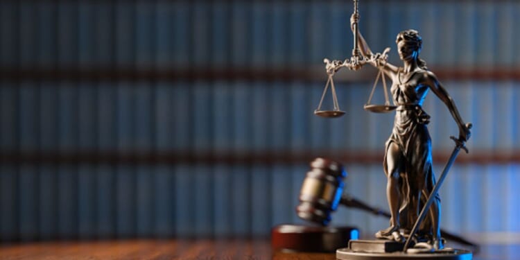 A statuette of Lady Liberty stands beside a gavel and a wooden block.
