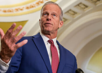 Low angle shot of John Thune with his right hand up.