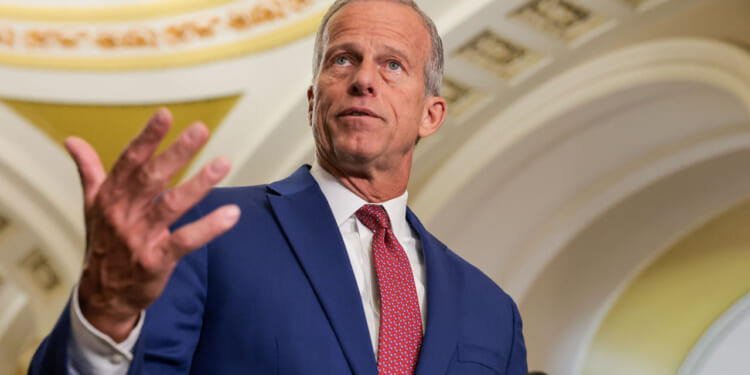 Low angle shot of John Thune with his right hand up.