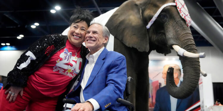 Aida Scott takes a photo with Governor Greg Abbott in front of an elephant named, Paige.
