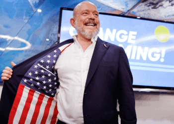 Steve Hilton stands on stage at his election night event smiling.