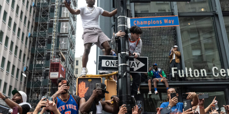 Fans can be seen climbing a lamp post during a parade.