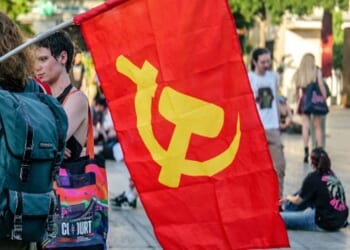 Protesters walk on campus with a communist flag displaying a hammer and sickle on June 19, 2026.
