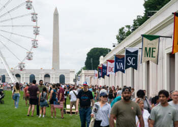 Visitors walk near the 110-foot "Freedom 250" ferris wheel on the third day of the "Great American State Fair" on the National Mall as seen looking toward the Washington Monument on June 27, 2026 in Washington, DC.