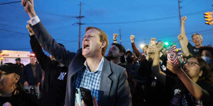A crowd of mostly white protesters raise fists in air.