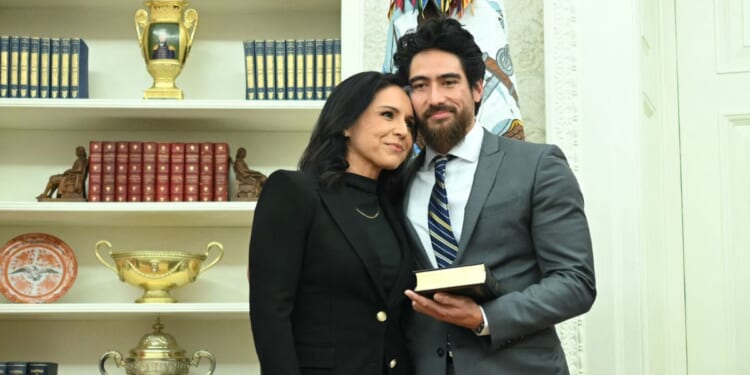Tulsi Gabbard and her husband, Abraham Williams, hug before she is sworn in as Director of National Intelligence in the Oval Office of the White House in Washington, D.C., on Feb. 12, 2025.