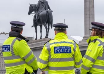 A group of three police officers in Trafalgar Square, Central London, on a chilly, grey day.