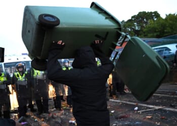 A man throws a garbage bin Tuesday as protesters confront riot police near the location where Henry Nowak died in Southampton, England.
