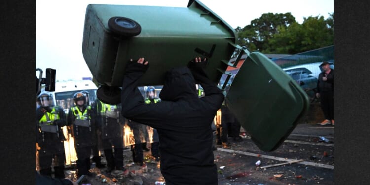 A man throws a garbage bin Tuesday as protesters confront riot police near the location where Henry Nowak died in Southampton, England.