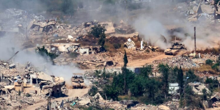 This picture taken from a position in the Upper Galilee in northern Israel, near the Israel-Lebanon border, shows Israeli Merkava tanks driving along a road past destroyed buildings in southern Lebanon on June 17, 2026.