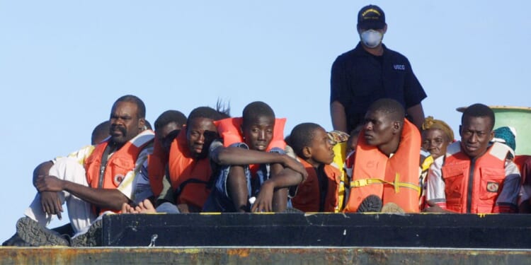 U.S. Coast Guard personnel watch over the 188 Haitians picked up Dec. 3, 2001, after their overloaded boat ran aground in 3 feet of water off the South Florida coast about 10 miles south of Miami.
