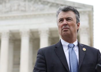 Alabama Attorney General Steve Marshall, a man in a suit and tie stands outside the Supreme Court, a large, white, classical-style building with columns. The sky is overcast, and he appears serious, looking slightly to the side.