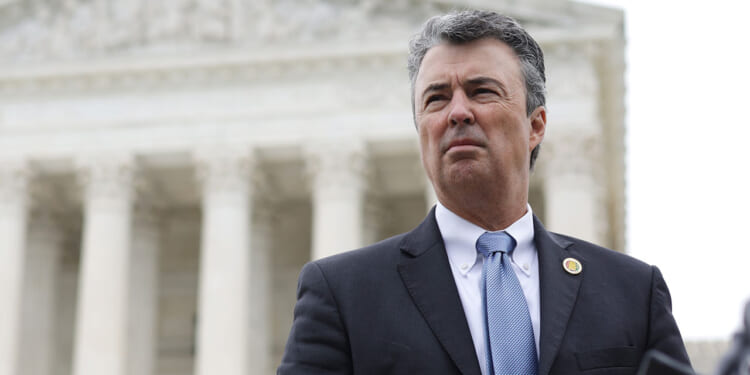 Alabama Attorney General Steve Marshall, a man in a suit and tie stands outside the Supreme Court, a large, white, classical-style building with columns. The sky is overcast, and he appears serious, looking slightly to the side.