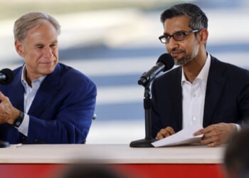 Texas Governor Greg Abbott and Alphabet and Google CEO Sundar Pichai sit at a table with microphones.