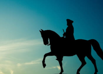 Silhouette of George Washington on his horse against a blue background.