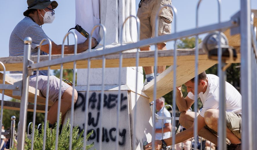 Volunteers clean the vandalized statue of the Virgin Mary, which has been covered with a white sheet, on Apparition Hill in Medjugorje, Bosnia, Tuesday, July 28, 2026. (AP Photo)
