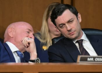 Democratic U.S. Sen. Jon Ossoff of Georgia, right, listens as Sen. Mark Kelly of Arizona whispers to him during a Senate March hearing.