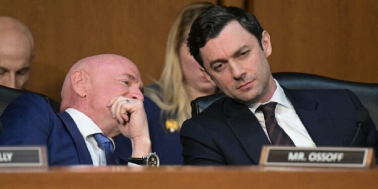 Democratic U.S. Sen. Jon Ossoff of Georgia, right, listens as Sen. Mark Kelly of Arizona whispers to him during a Senate March hearing.