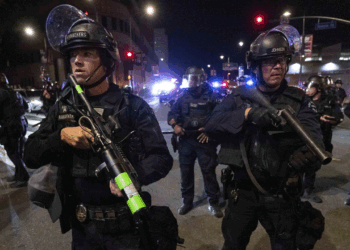 Police in riot gear stand guard.