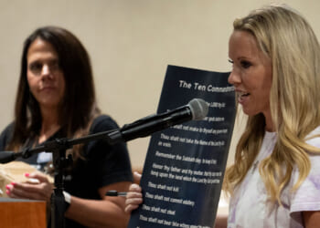 Rebecca Smith speaks while holding a poster displaying the Ten Commandments, as she and volunteers distribute posters displaying religious text for schools during a Conroe ISD school board meeting in Conroe, Tuesday, Aug. 19, 2025.