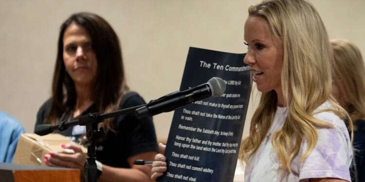Rebecca Smith speaks while holding a poster displaying the Ten Commandments, as she and volunteers distribute posters displaying religious text for schools during a Conroe ISD school board meeting in Conroe, Tuesday, Aug. 19, 2025.