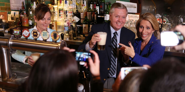 Dana Bash, Senator Lindsey Graham, and his sister Darline Graham Nordone serve guests prior to CNN's Politics On Tap at Walnut Brewery on October 27, 2015 in Boulder, Colorado.