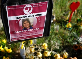Flowers and signs are seen in a makeshift memorial in front of the home of Nancy Guthrie on Feb. 27 in Tucson, Arizona. Guthrie went missing from her home on the morning of Feb. 1.