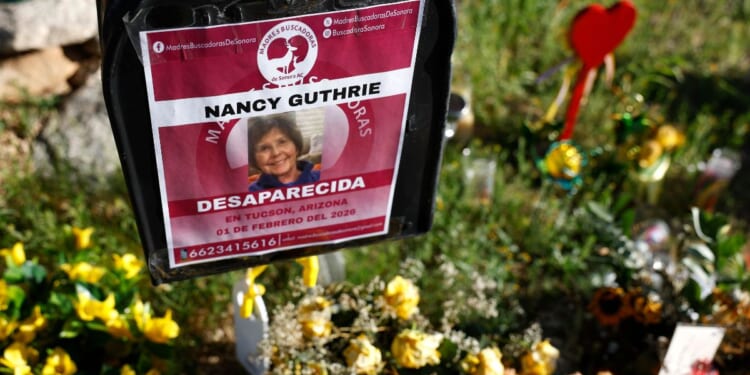 Flowers and signs are seen in a makeshift memorial in front of the home of Nancy Guthrie on Feb. 27 in Tucson, Arizona. Guthrie went missing from her home on the morning of Feb. 1.