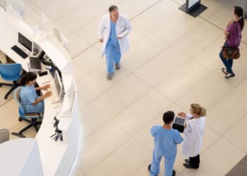 Hospital staff walk around in a hospital foyer.