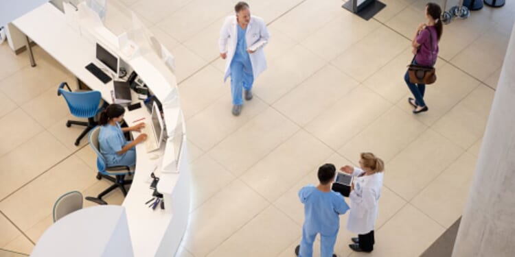 Hospital staff walk around in a hospital foyer.