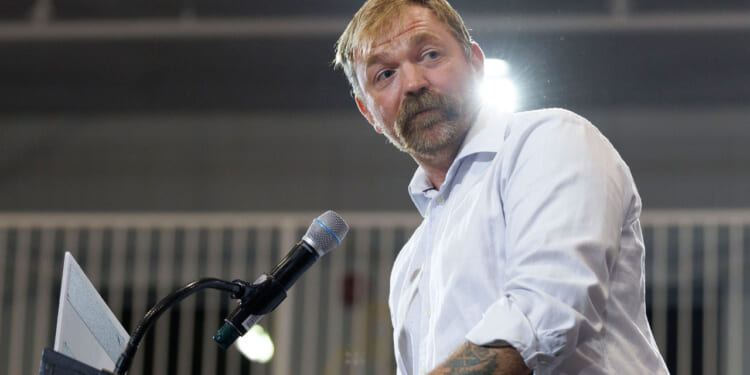 Democrat Graham Platner looks off to the side as he speaks at a podium.