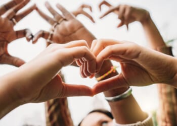 People hold up their hands with heart signs.