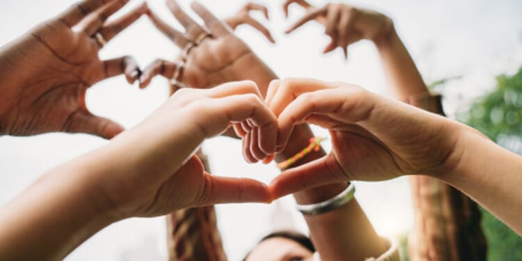 People hold up their hands with heart signs.