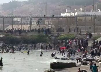 This video frame grab obtained from an AFP video shows migrants reaching the shore of Spanish north African exclave of Ceuta, after swimming around the border fence between Morocco and Spain, in Ceuta on July 30, 2026.