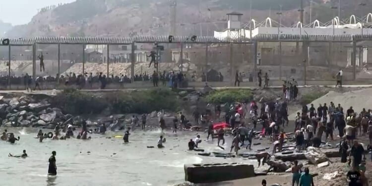 This video frame grab obtained from an AFP video shows migrants reaching the shore of Spanish north African exclave of Ceuta, after swimming around the border fence between Morocco and Spain, in Ceuta on July 30, 2026.