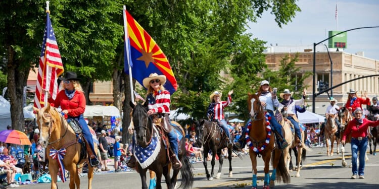 A female participant riding a horse while holding a flag in Prescott, Arizona, on July 3, 2021.
