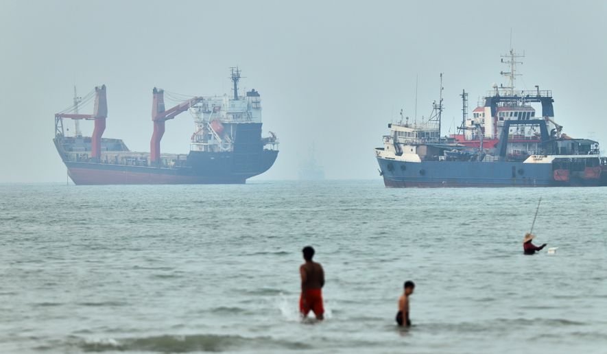 Children wade in the water with cargo ships at anchor in the background and a fisherman nearby, in the Strait of Hormuz off Bandar Abbas, Iran, Tuesday, June 30, 2026. (Amirhosein Khorgooi/ISNA via AP, File)