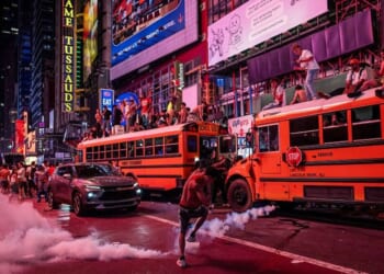 A person kicks a smoke canister as New York Knicks fans celebrate their win against San Antonio Spurs in Game 5 of the NBA Finals June 14 in Times Square in New York City. One exuberant fan reportedly set fire to a school bus.