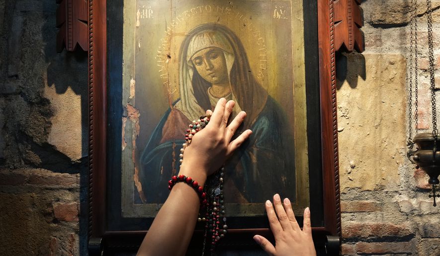 Catholics touch one of the images of Mary inside the Ephesus House, a replica of the House of the Virgin Mary in Ephesus, Turkey, at Alfonso town, Cavite province, Philippines on July 16, 2026. (AP Photo/Aaron Favila)