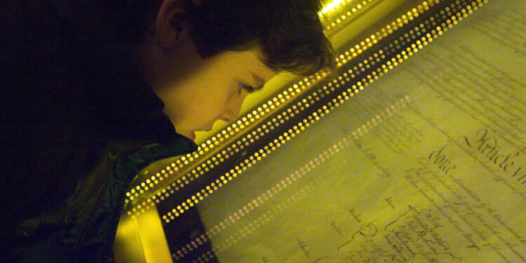 Close-up of a boy looking through a glass frame at the U.S. Constitution.
