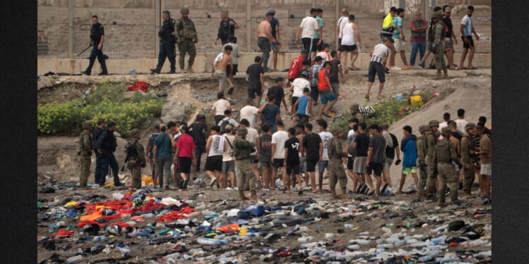 Spanish soldiers direct migrants back to Morocco after they crossed the border to enter Spain's north Africa's Ceuta territory on Thursday. In recent days, a total of around 60,000 migrants have crossed into the territory, whose population is 80,000.