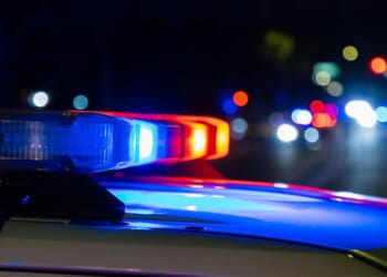 A crime scene in a city at night with blue and red police lights.