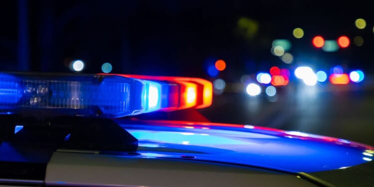 A crime scene in a city at night with blue and red police lights.