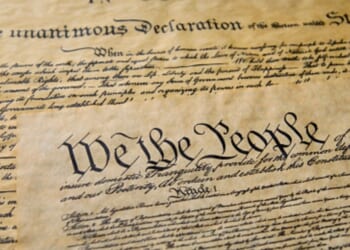 Pages of the Constitution are visible under warm lighting.