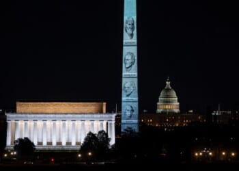 The Washington Monument stands illuminated with Founding Fathers’ faces on January 3, 2026.
