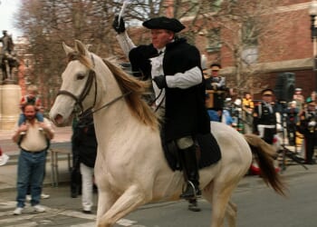 A Paul Revere reenactor rides on a horse