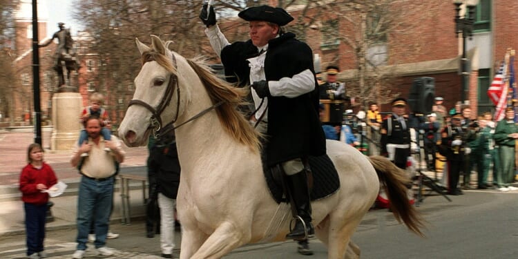 A Paul Revere reenactor rides on a horse