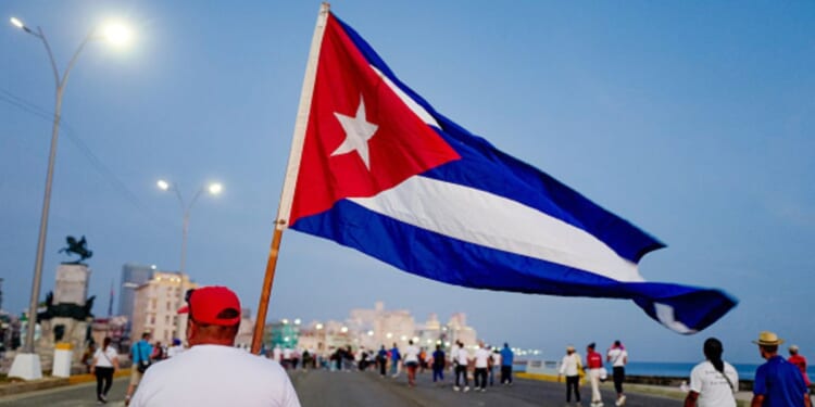 A man walks with a Cuban flag alongside the Havana waterfront on May 1, 2026.